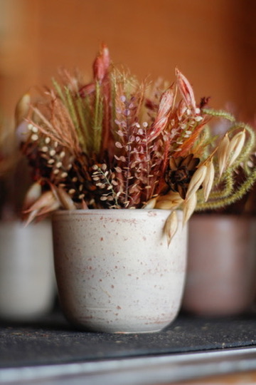 Arranjo de flores secas em vaso cerâmico claro